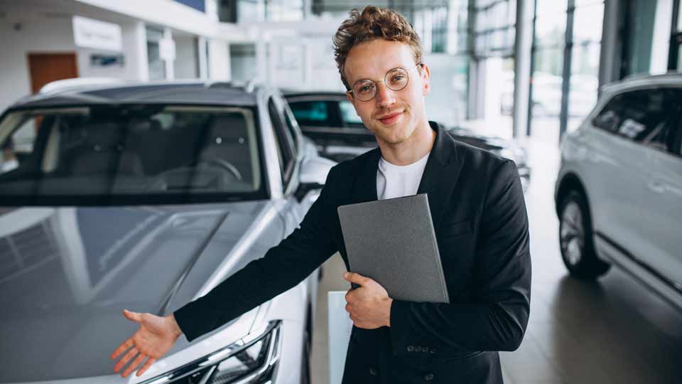 Ein Verkäufer zeigt auf ein Auto und erklärt dem Kunden die Konditionen beim Auto verkaufen Erfurt